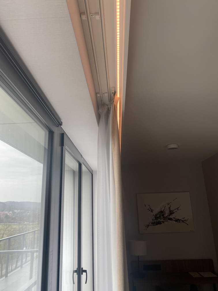 Riel de cortina decorativo con iluminación LED en techo, junto a ventanal de sala moderna