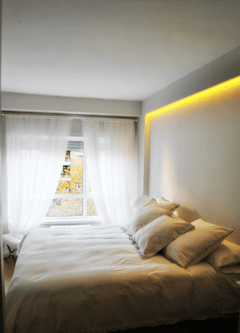Dormitorio moderno con pared blanca y moldura decorativa iluminada con luz LED cálida