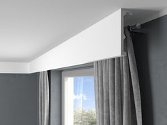 Moldura decorativa blanca en techo moderno cubriendo barra de cortina gris