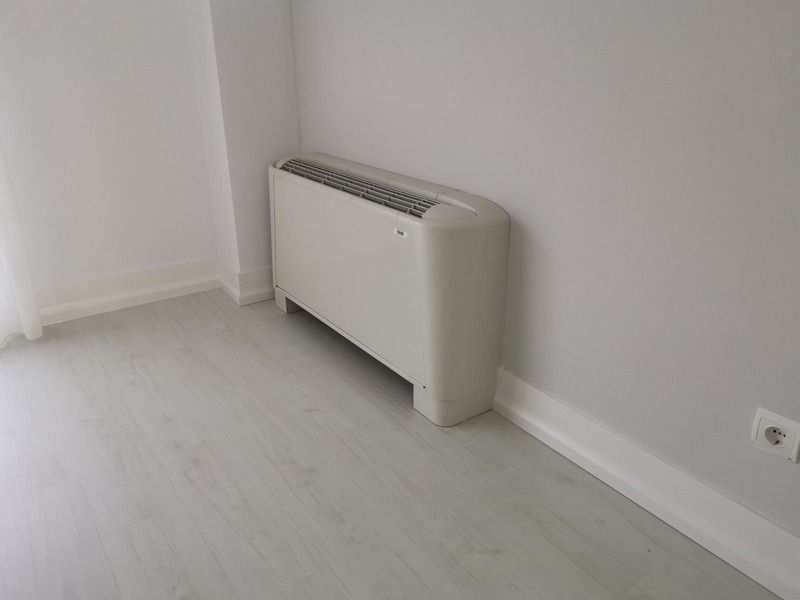 Rodapié blanco moderno en esquina de habitación con suelo laminado claro