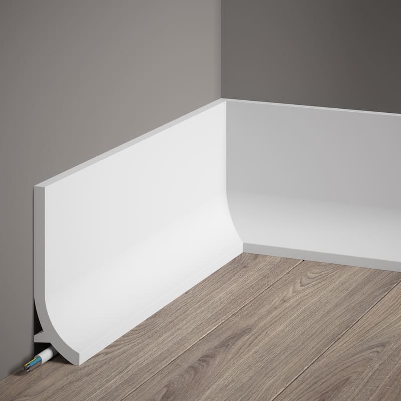 Rodapié blanco moderno de gran tamaño en esquina, sobre suelo de madera y pared gris.