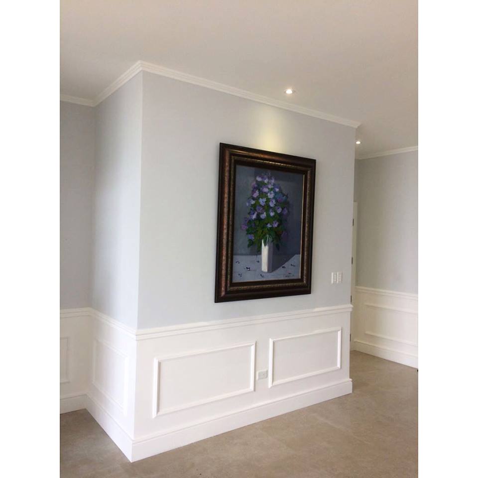 Rodapié de PVC alto blanco en pared interior con moldura decorativa y suelo claro.