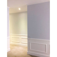 Pared interior con molduras decorativas blancas y rodapié en estilo clásico elegante.