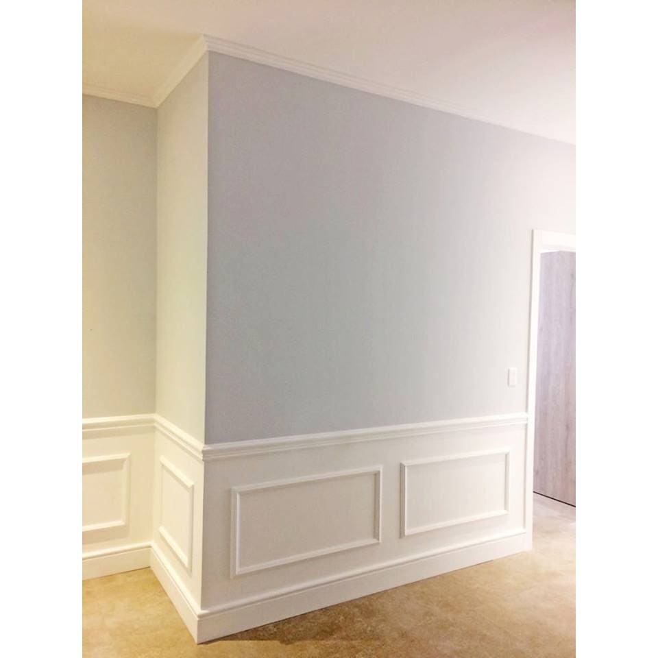 Pared interior con molduras decorativas blancas y rodapié, diseño elegante y clásico.