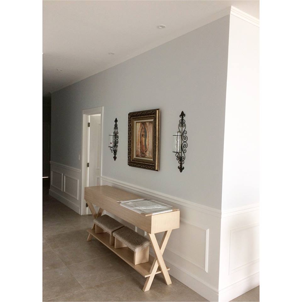 Recibidor elegante con molduras decorativas blancas, consola de madera y rodapiés clásicos.