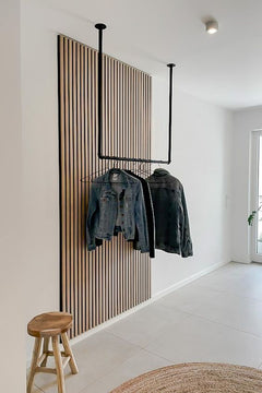 Recibidor moderno con panel decorativo de listones de madera y perchero de techo negro.