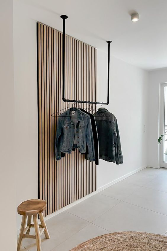 Recibidor moderno con panel decorativo de listones de madera y perchero de techo negro.