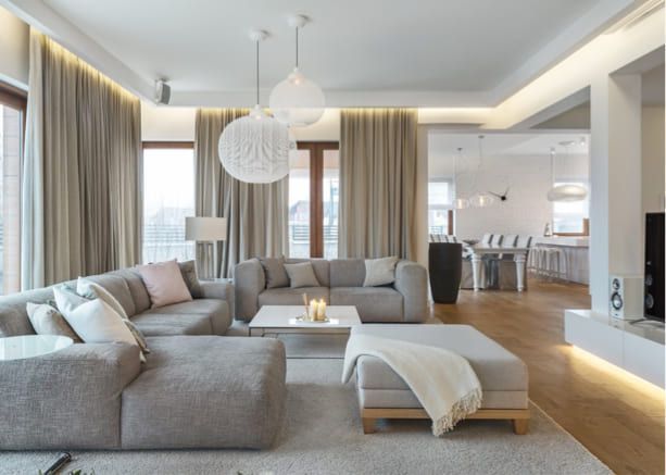Sala moderna con cortinero decorativo, cortinas beige y sofá gris en ambiente luminoso