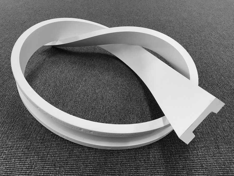 Moldura decorativa flexible blanca para pared sobre alfombra gris