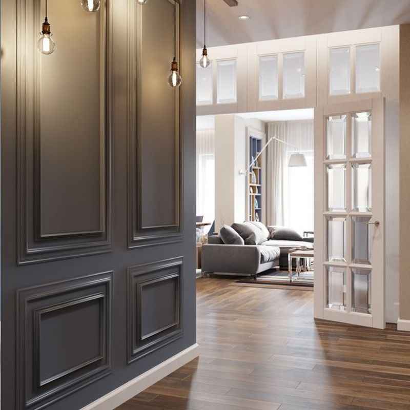 Pared decorativa con molduras clásicas y suelo de madera en sala moderna luminosa