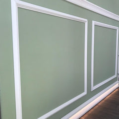 Molduras decorativas blancas en pared verde, diseño elegante para interiores modernos
